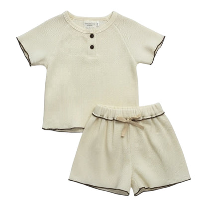 Cream waffle-textured baby top and shorts set with contrast ruffle-edge stitching, displayed flat on a white background.