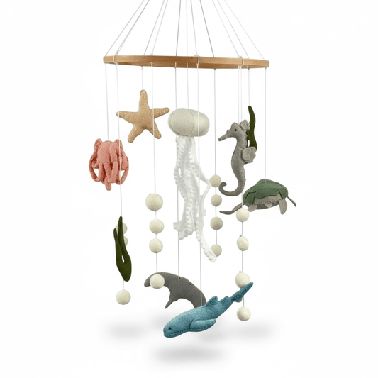 Hand-felted under-the-sea cot mobile with jellyfish, seahorse, octopus, starfish, turtle, stingray, and shark hanging from a wooden ring, 65 cm drop, on white background.
